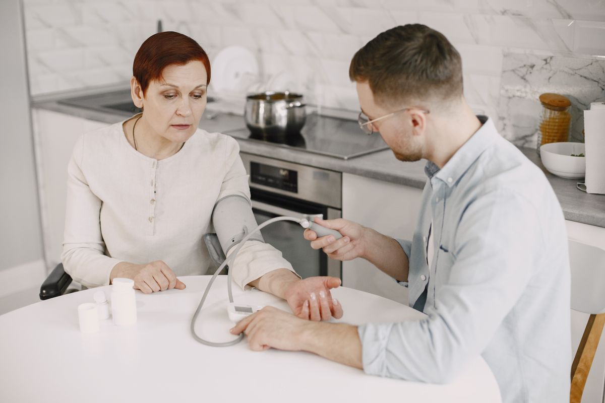 Caregiver checking an older adult's vital signs